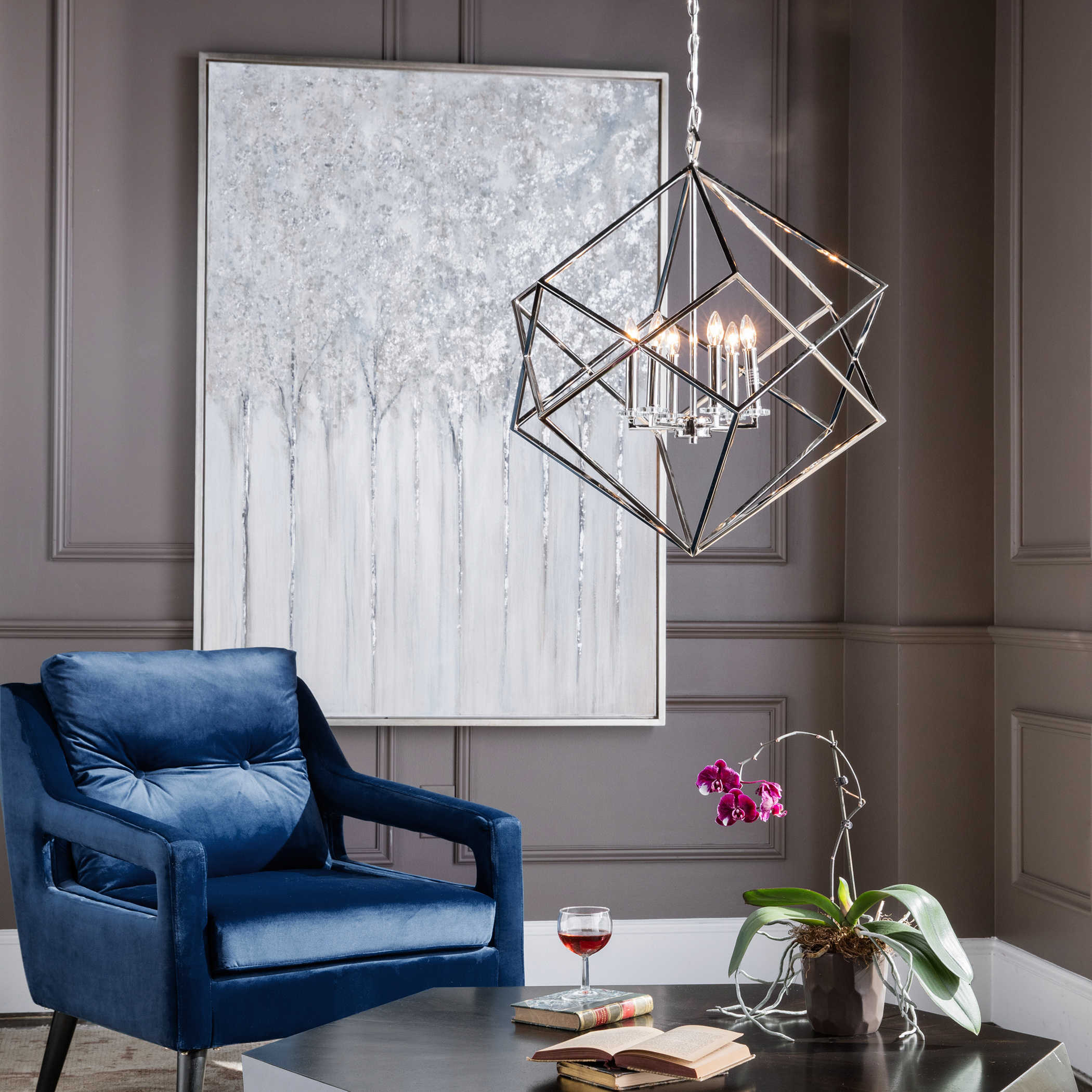 An elegant, polished nickel cube interlocked with its twin, at the center of their intersection is a 6 light candle cluster with mini crystal bobeches.